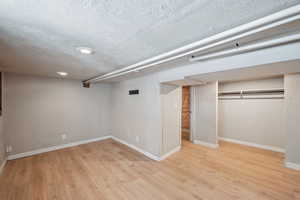 Finished basement with wood finished floors, baseboards, a textured ceiling, and recessed lighting