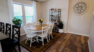 Dining area with dark wood-style flooring and baseboards