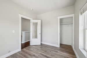 Unfurnished bedroom with wood finished floors, a closet, and baseboards