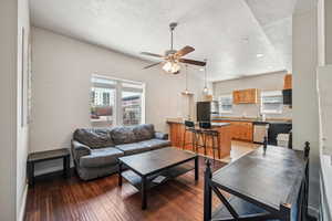 Living area with a textured ceiling, a ceiling fan, light wood-type flooring, recessed lighting, and baseboards