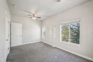 Carpeted spare room with ceiling fan, baseboards, and a smoke detector