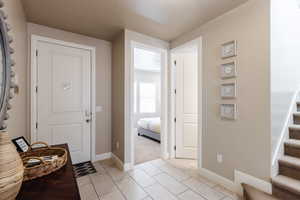 Entryway featuring stairs, baseboards, and light tile patterned floors