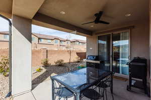View of patio featuring a ceiling fan, fence, outdoor dining space, and a residential view