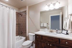 Bathroom featuring toilet, vanity, and shower / bath combination with curtain