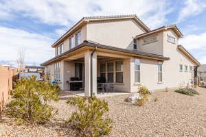 Rear view of house featuring fence, a patio area, and stucco siding