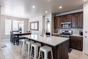 Kitchen with appliances with stainless steel finishes, a sink, tasteful backsplash, a breakfast bar, and an island with sink