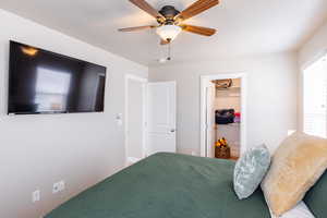 Bedroom with ceiling fan and a walk in closet