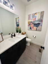 Bathroom with toilet, vanity, and baseboards