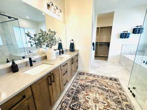 Bathroom with a stall shower, double vanity, a relaxing tiled tub, baseboards, and recessed lighting