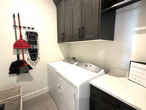 Laundry area featuring cabinet space, washing machine and clothes dryer, baseboards, and light wood-type flooring