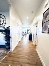 Hallway featuring wood finished floors, baseboards, and recessed lighting
