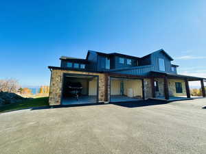 View of front facade featuring board and batten siding, stone siding, a garage, and asphalt driveway