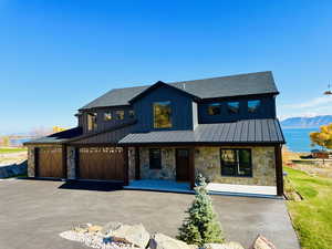 Modern inspired farmhouse with stone siding, covered porch, a standing seam roof, board and batten siding, and roof with shingles