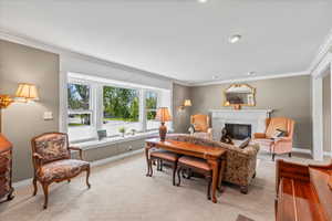 Living area with a premium fireplace, ornamental molding, light carpet, and baseboards