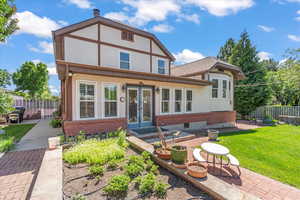 View of front facade featuring french doors, a patio, brick siding, and stucco siding