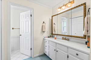 Bathroom with ornamental molding, vanity, tile patterned flooring, and baseboards