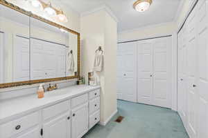Bathroom featuring a closet, crown molding, vanity, and baseboards