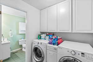 Washroom featuring independent washer and dryer, baseboards, light tile patterned floors, and a sink