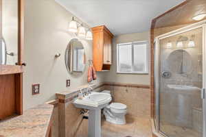 Bathroom featuring a shower stall, a textured ceiling, tile patterned flooring, tile walls, and toilet