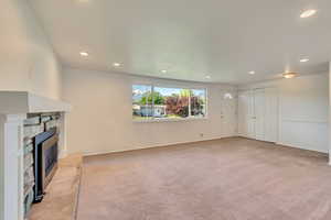 Unfurnished living room featuring light carpet, a fireplace, and recessed lighting