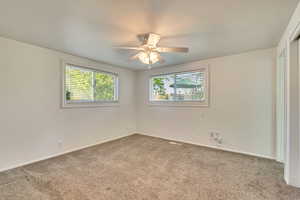 Unfurnished Primary bedroom with carpet flooring, baseboards, and a ceiling fan