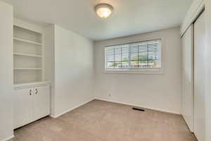 Unfurnished bedroom with light carpet, baseboards, and a closet