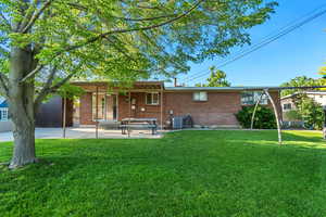 Rear view of property featuring brick siding, a patio, a yard, and central AC unit