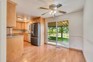 Kitchen with stainless steel fridge with ice dispenser, light countertops, light brown cabinetry, dishwasher, and light wood finished floors