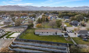 Aerial view of property and surrounding area featuring a mountainous background and nearby suburban area