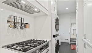 Kitchen with stacked washer / dryer, stainless steel gas stove, white cabinets, baseboards, and recessed lighting