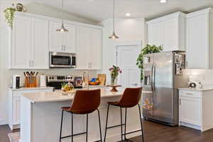 Kitchen featuring stainless steel appliances, dark wood-style flooring, recessed lighting, white cabinetry, and lofted ceiling