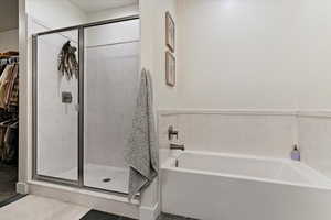 Full bathroom with a stall shower, a bath, and a spacious closet