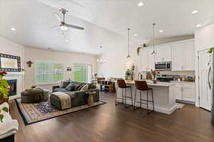 Living area featuring ceiling fan, dark wood finished floors, lofted ceiling, a large fireplace, and recessed lighting