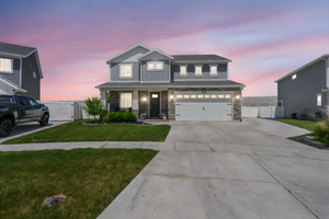 View of front of home featuring a gate, concrete driveway, a garage, stone siding, and board and batten siding, large RV Pad