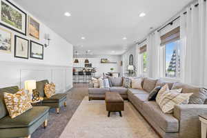 Living room with recessed lighting, light carpet, a decorative wall, and a wainscoted wall