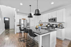 Kitchen with stainless steel appliances, backsplash, baseboards, recessed lighting, and light wood finished floors