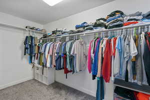 Primary bedroom spacious closet featuring carpet flooring and tons of storage