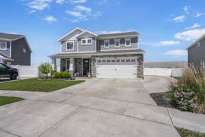 View of front home  with large driveway, stone siding, an attached garage, and board and batten siding, large RV Pad