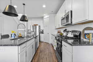Kitchen with appliances with stainless steel finishes, a sink, white cabinets, and recessed lighting