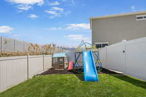 View of yard featuring a playground, a storage unit, and an outbuilding