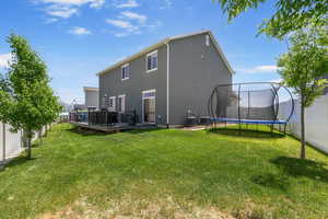 Rear view of house with a trampoline, a wooden deck, central air condition unit, and stucco siding