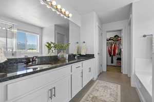 Primary suite bathroom with double vanity, a bath, a spacious closet, tile flooring, and a shower