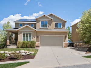 View of front of home featuring driveway, roof mounted solar panels, a garage, and stucco siding