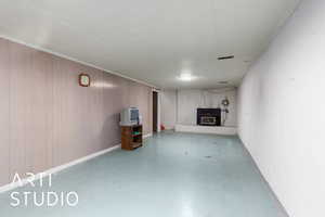 Finished basement with a brick fireplace, tile patterned floors, and wooden walls