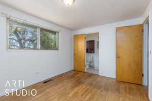 Unfurnished bedroom with light wood-style flooring, baseboards, and connected bathroom