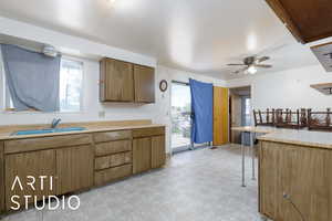 Kitchen featuring a sink, light flooring, a ceiling fan, and light countertops
