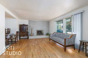 Living room featuring light wood-style flooring, a fireplace, and a textured ceiling