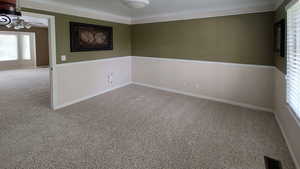 Unfurnished room featuring a ceiling fan, crown molding, carpet floors, and baseboards