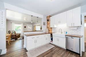Kitchen featuring dishwasher, wooden counters, a sink, and dark wood-style floors