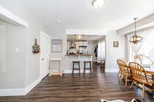 Dining area featuring dark wood-type flooring, baseboards, and a chandelier